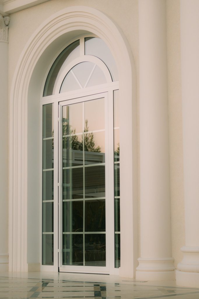 Elegant arched window reflecting a serene outdoor scene, framed by classical architecture.