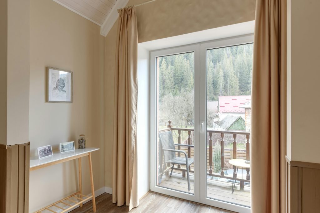 Inviting room with a balcony, showcasing a serene forest view through large windows.